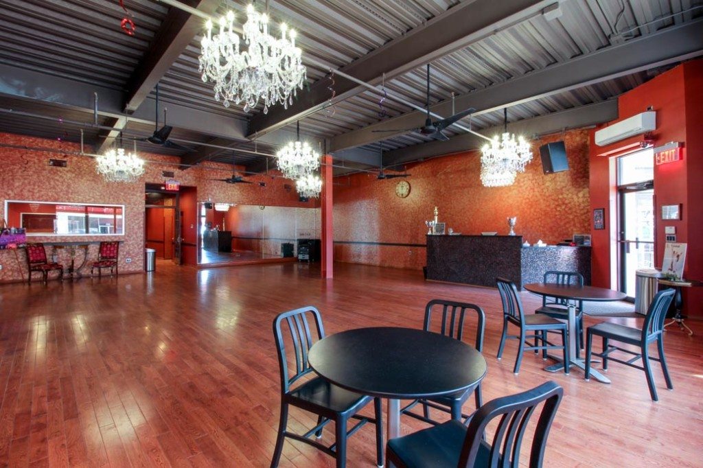 Dance studio with open dance floor and chandeliers.