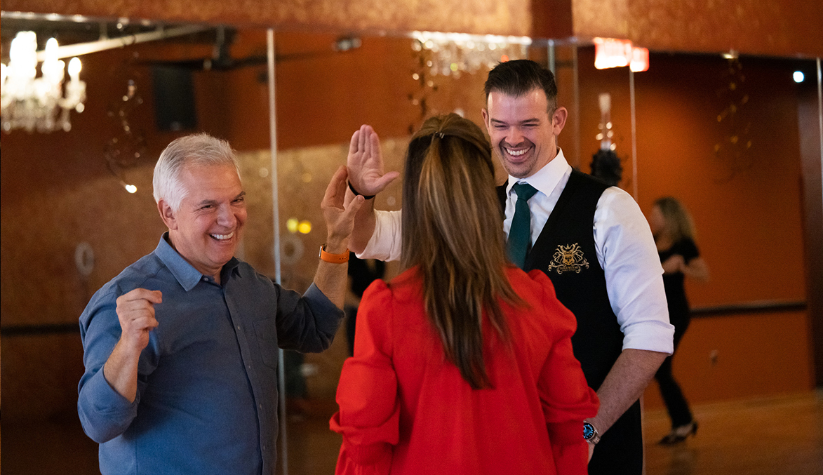 Dance couple smiles and high-fives' their DWM teacher.