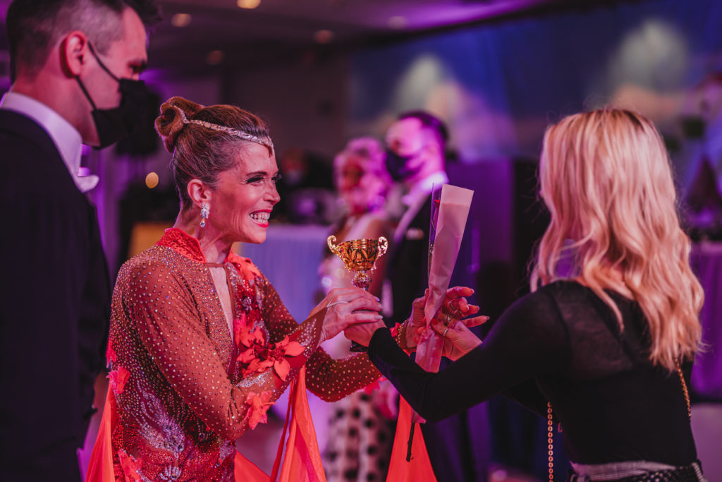 Lady is happily accepting a dancesport competition trophy.