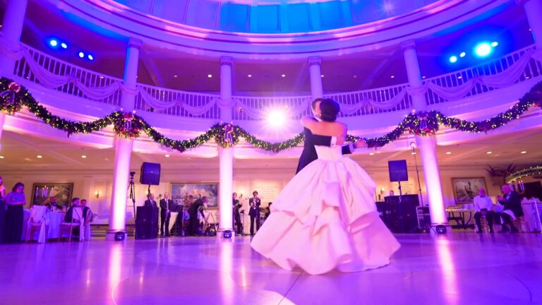 Bride and groom dancing their first dance alone on a ballroom floor while wedding guests watch from the edges
