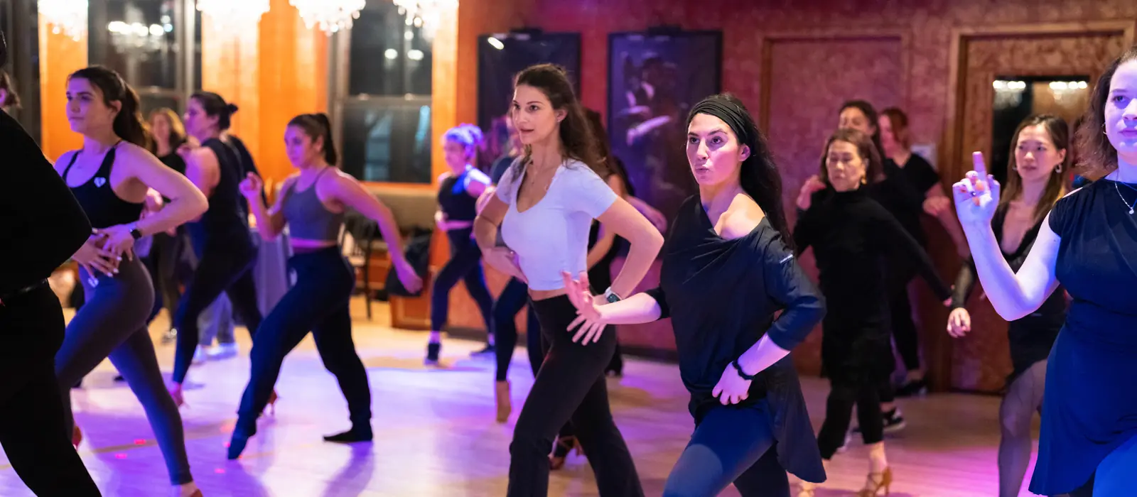 Adults dancing a line dance together in rows during a beginner group class at Dance With Me