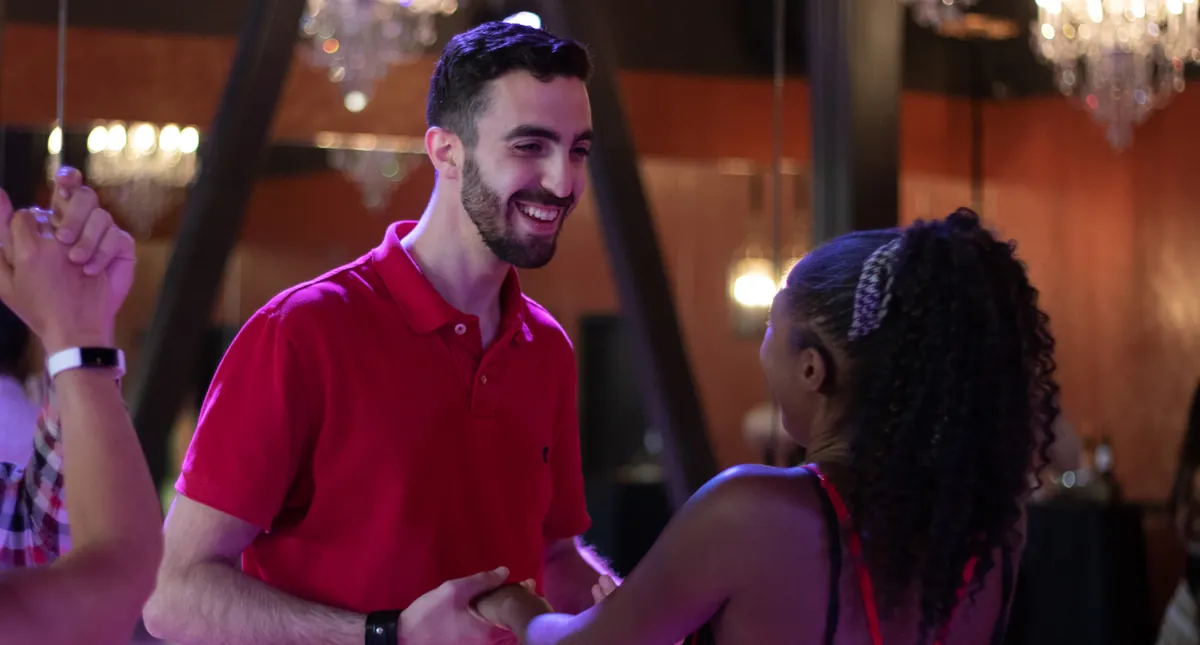 A laughing couple holding hands mid-step during a partner dance lesson