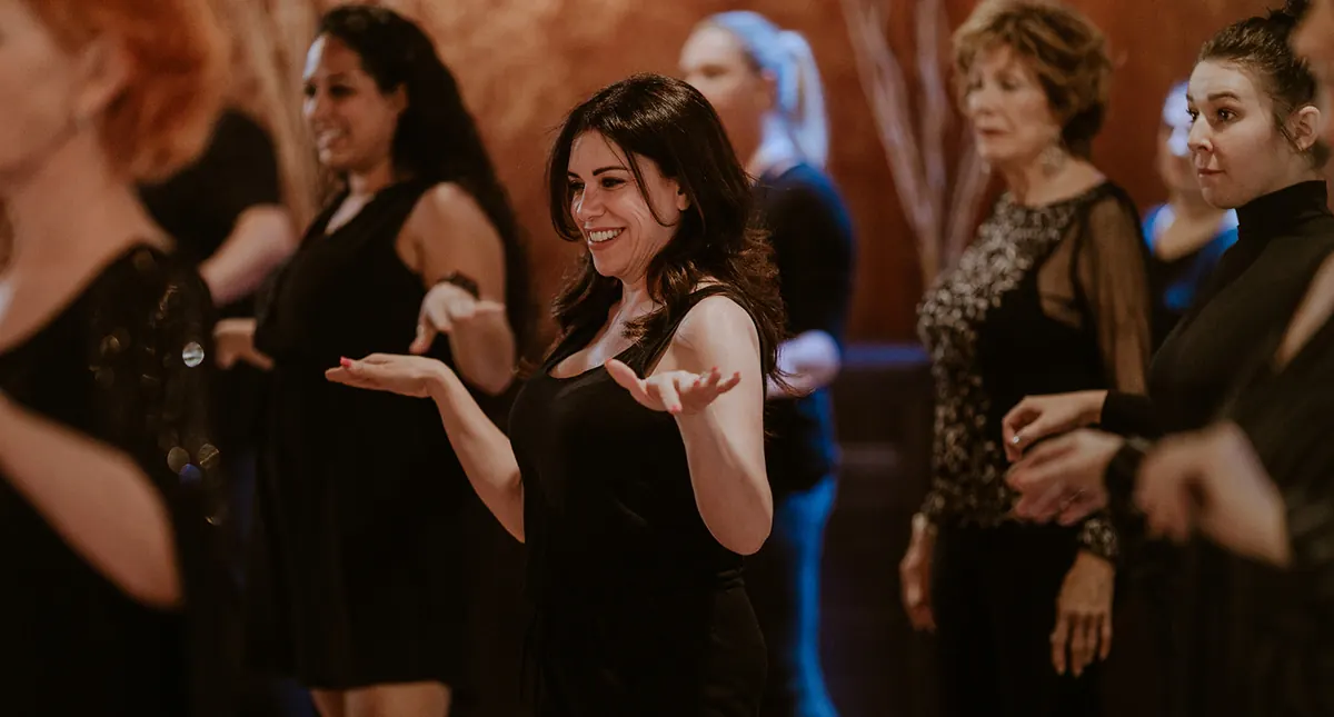 A group of women laughing as they learn a dance together