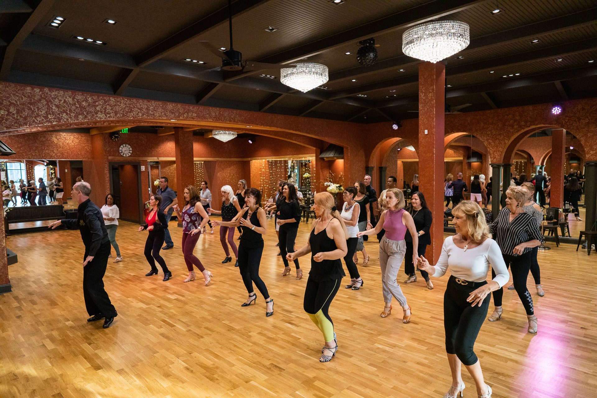 Adult salsa group class practicing shines in rows