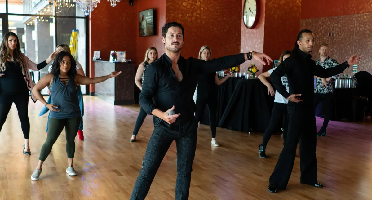 An instructor demonstrating a Latin step while adult students follow in a group class in Houston
