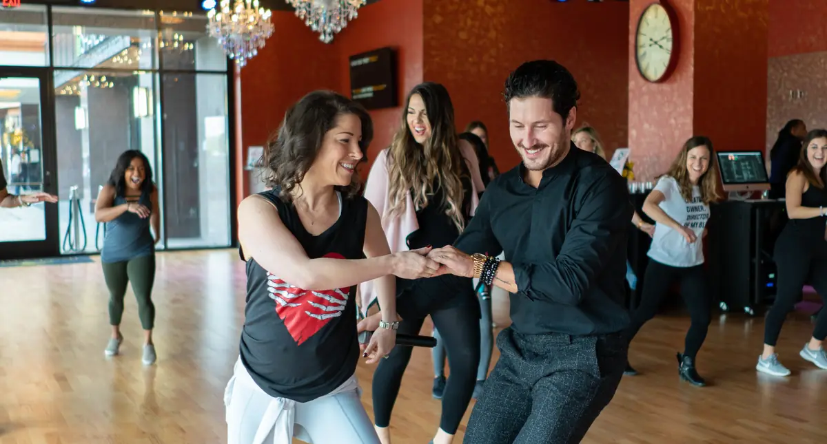 An instructor leading a smiling student through a partnered turn in a dance lesson in Houston