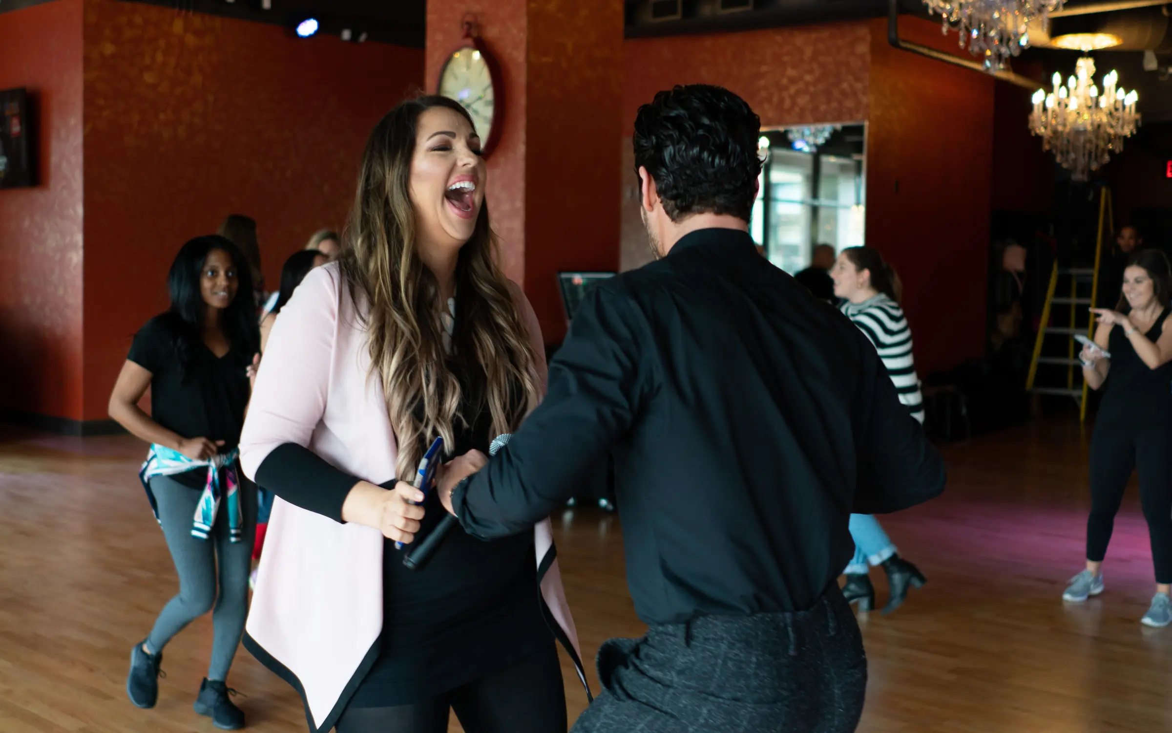 A woman laughing as her instructor leads her into a salsa turn during a dance class in Houston